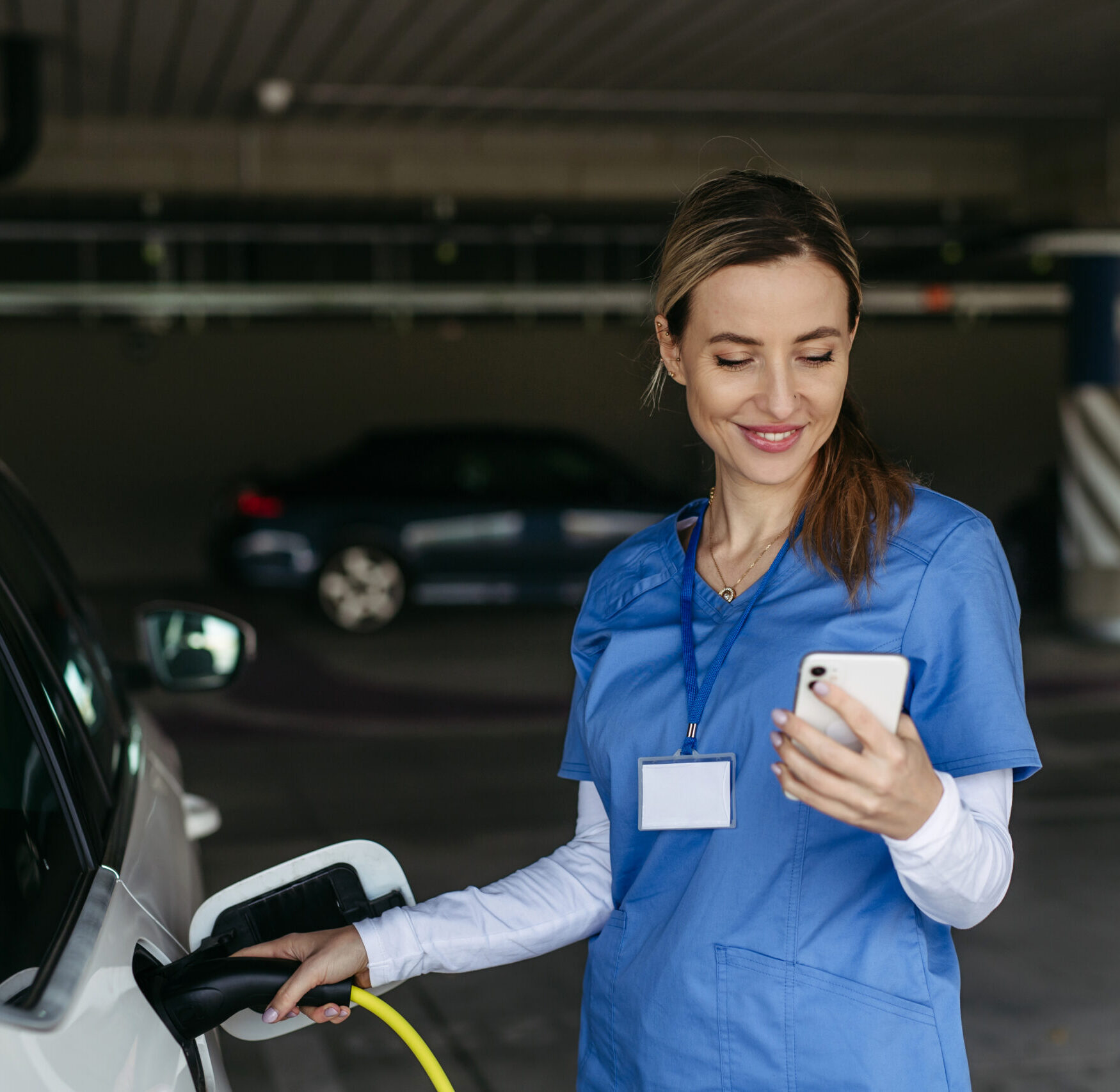 healthcare parking consultants, image of nurse in parking garage unpluging an electric car.