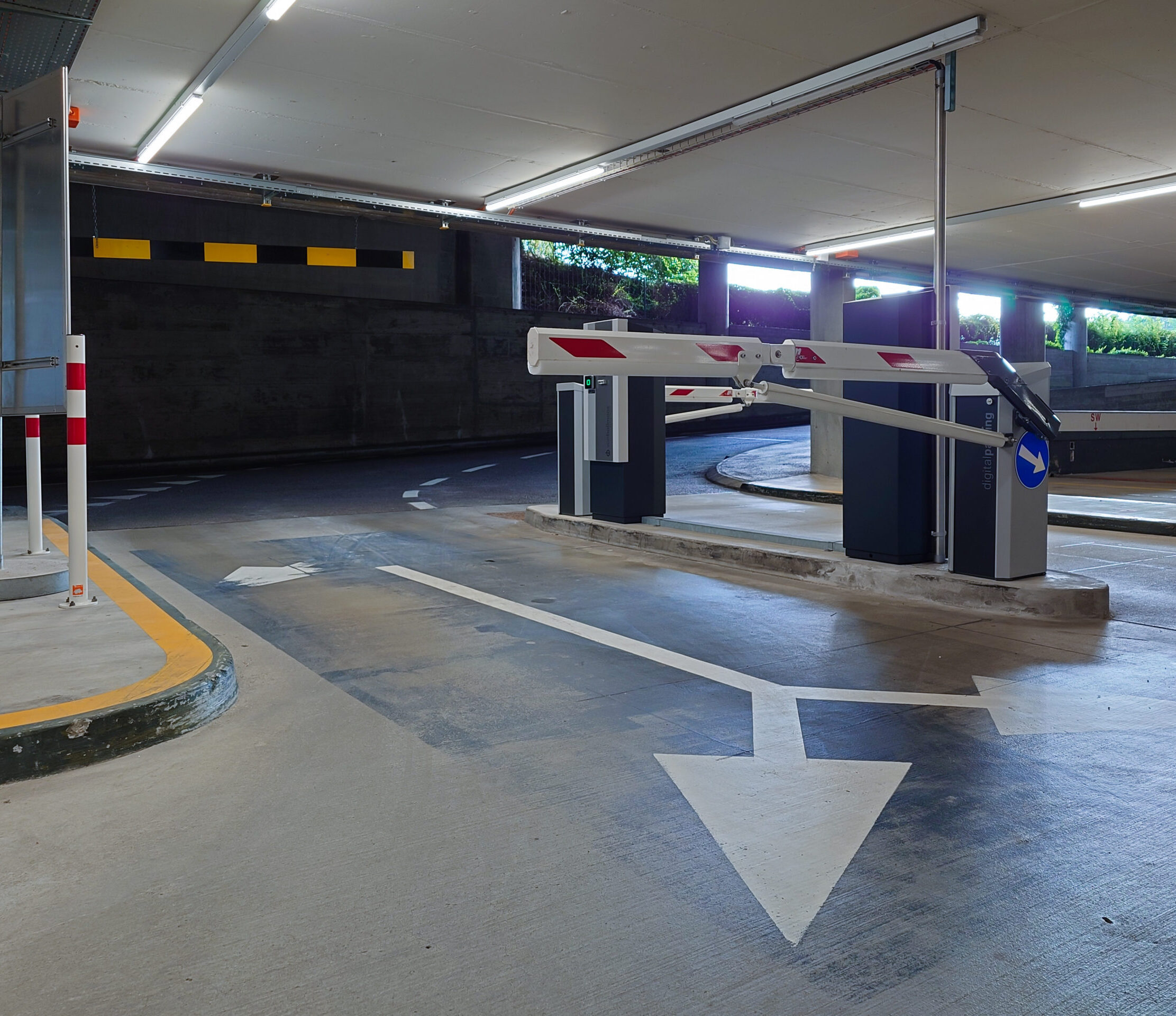 parking control systems Underground large car park entrance and exit lanes with ticket dispensers and barriers. No people